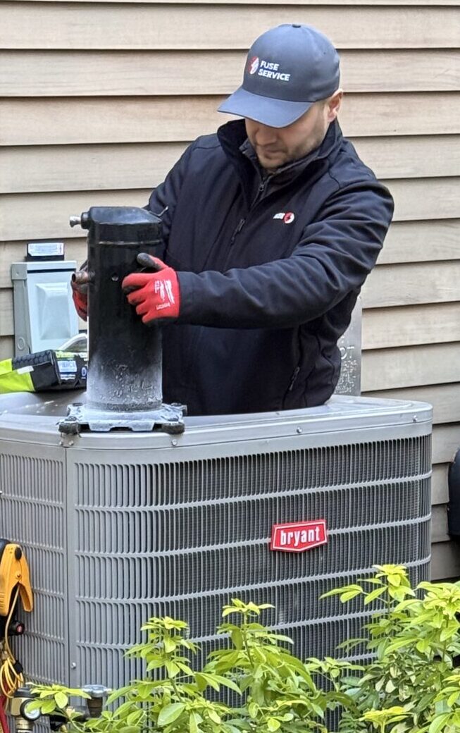 HVAC technician performing outdoor maintenance on residential equipment.
