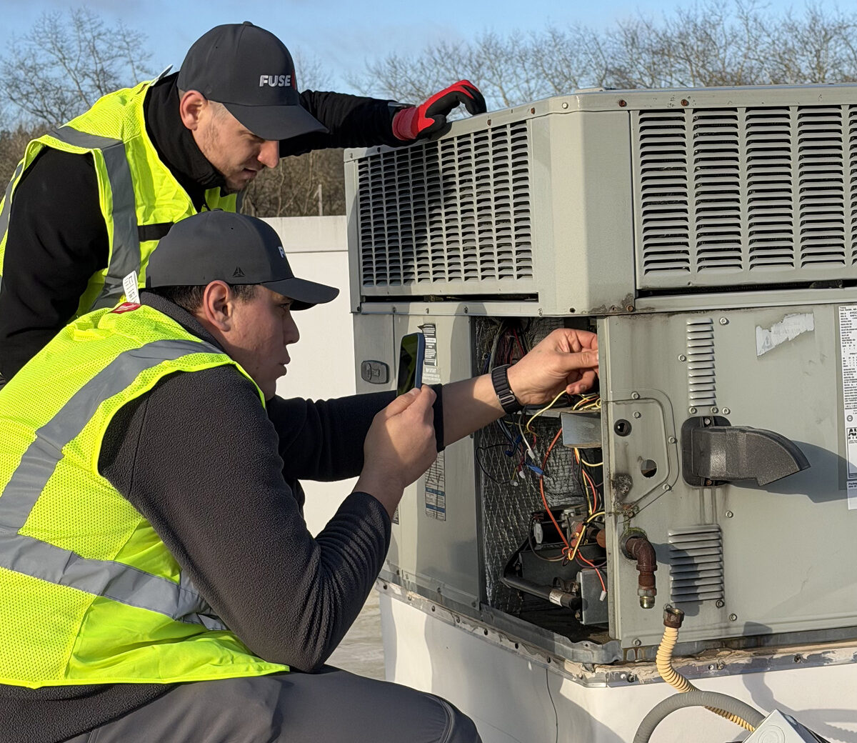 HVAC technician servicing a rooftop RTU unit.